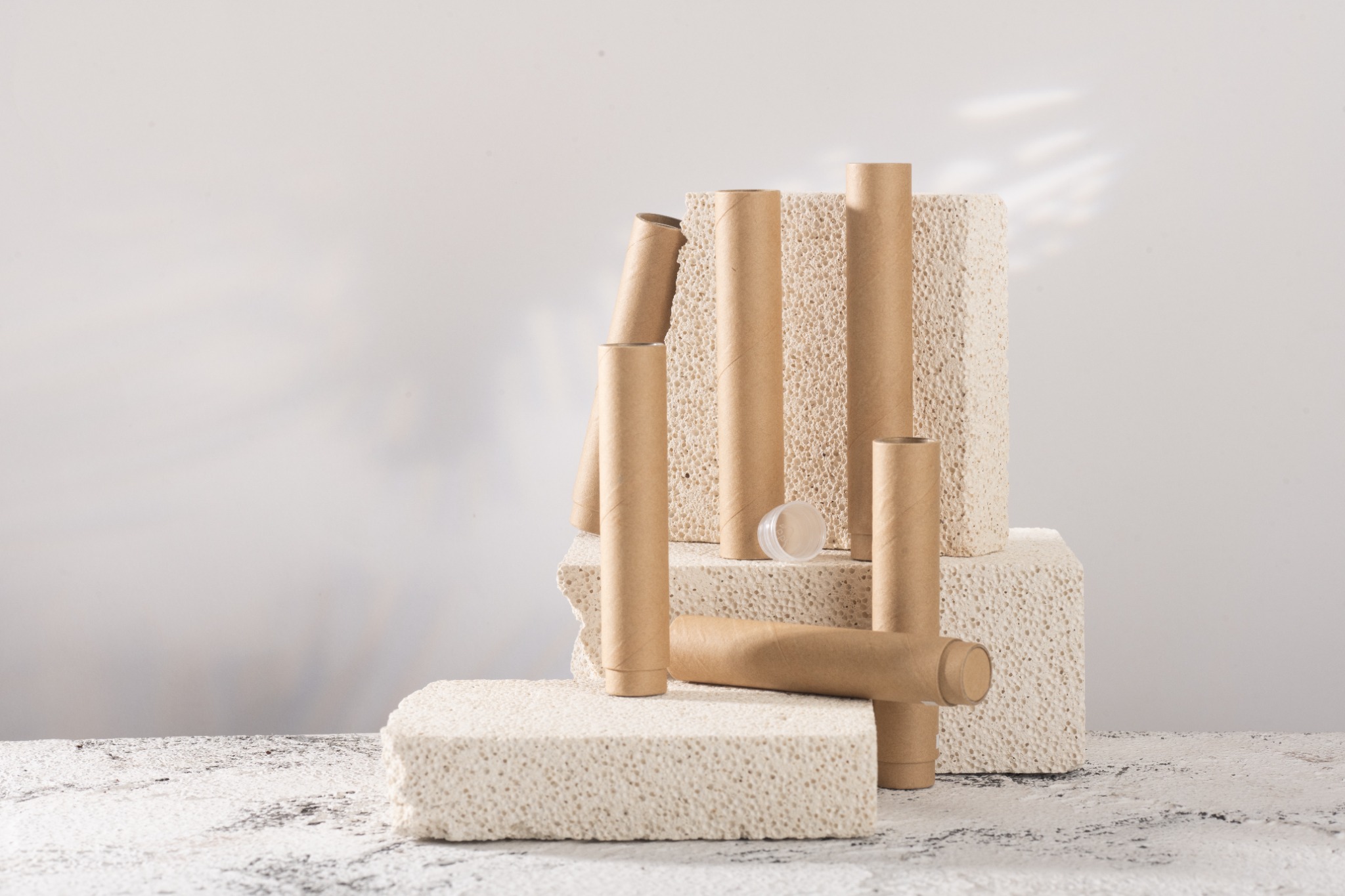 A collection of kraft paper tubes arranged on pale stone plinths