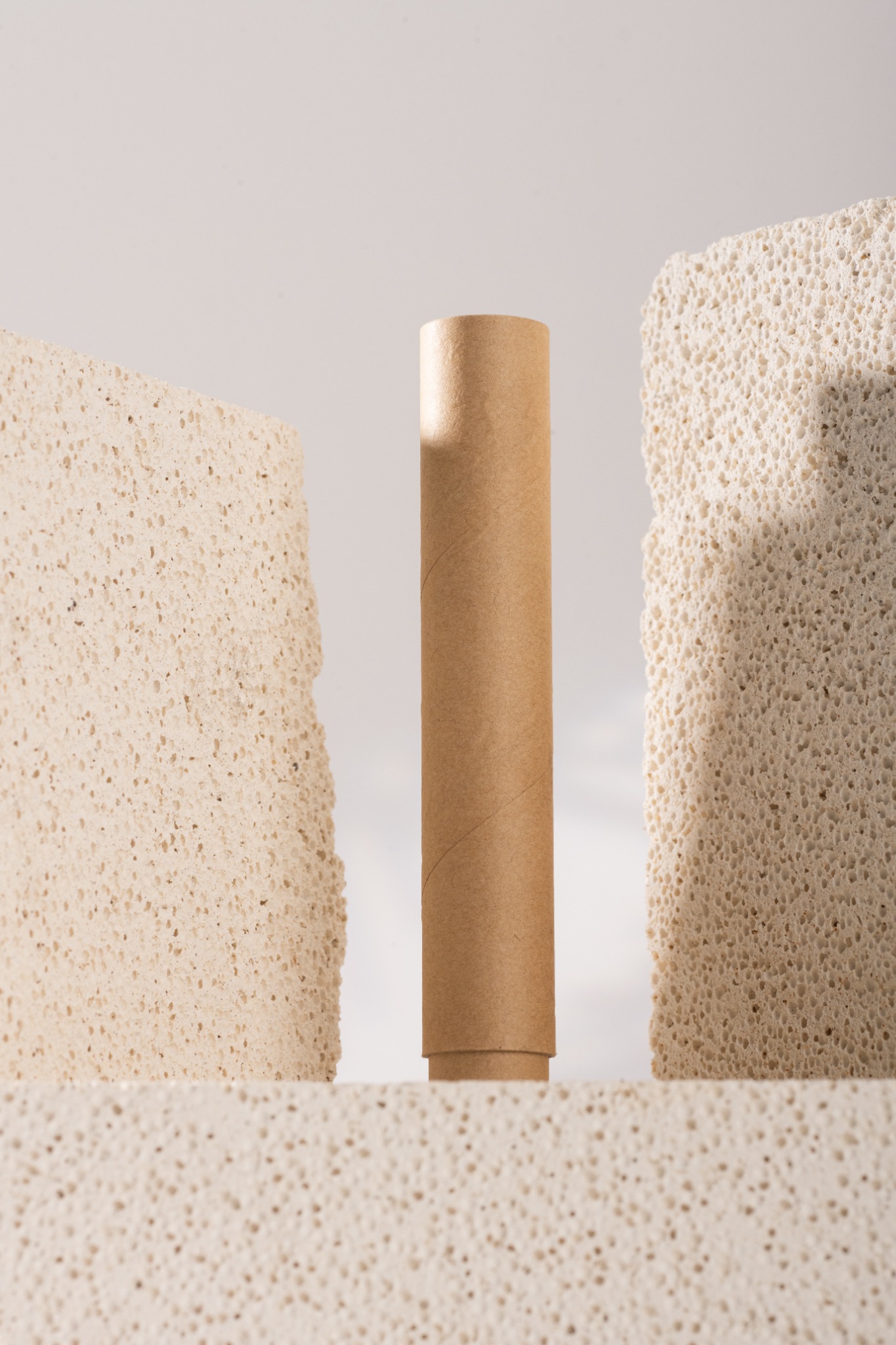 A single kraft paper tube between pale textured stone blocks